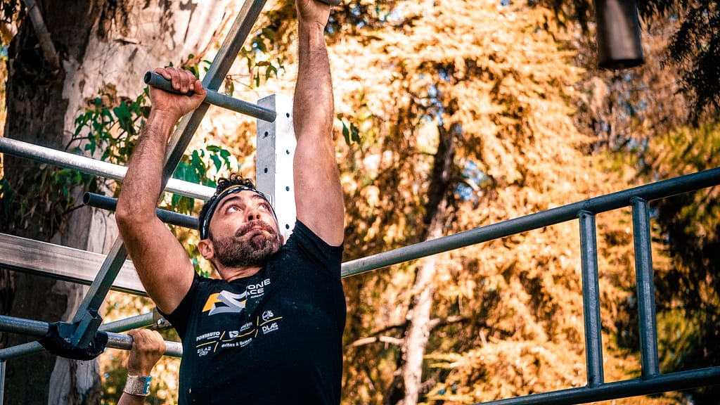 Course d'obstacle.
un homme se balance de barre en barre avec ses pieds dans le vide